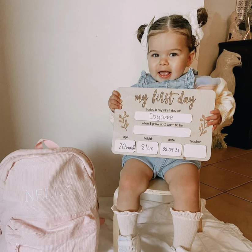 toddler girl holding a first day board 